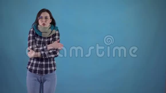 4戴着围巾的冻僵的年轻女子站在蓝底不起来视频的预览图