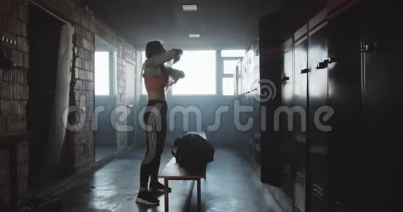 美丽的年轻运动白人妇女在黑暗的健身房更衣室锻炼后换衣服动机概念视频的预览图
