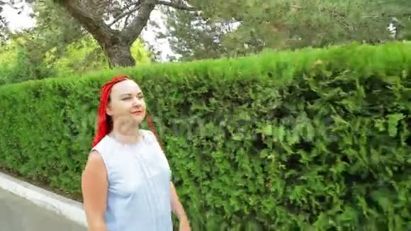 一个红头发的女人沿着绿地散步视频的预览图