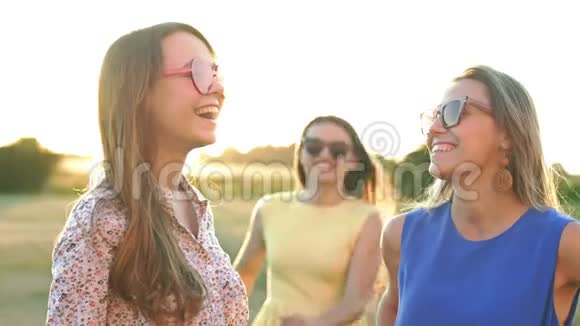 在温暖的夏日里三个朋友在街上拥抱的快乐会议三个戴太阳镜的女孩视频的预览图
