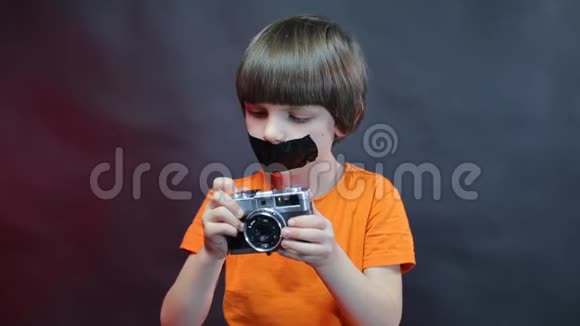 一个嘴巴紧闭的男孩手里拿着相机视频的预览图