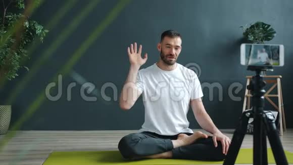 男性瑜伽老师使用智能手机相机录制教程视频的预览图