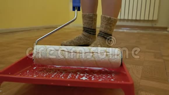 女孩用白色油漆在平底锅里浸泡一个建筑滚筒房间内的自我修复视频的预览图