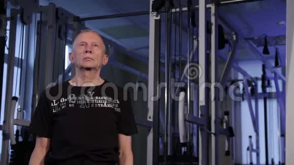 一个同龄男人在健身房为肩膀做关节体操肩膀旋转闪烁摄像机镜头视频的预览图