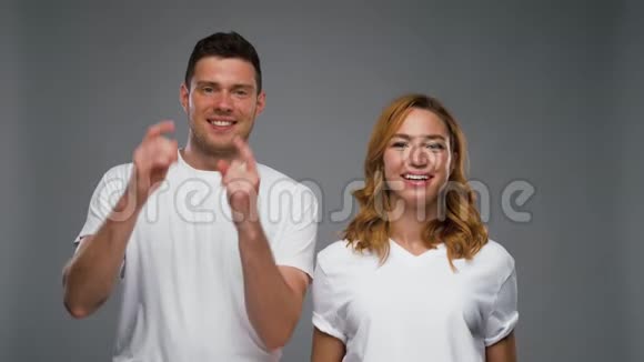 一对穿着白色t恤衫的夫妇在灰色的上空打手势视频的预览图