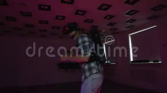 虚拟现实耳机里的年轻人正在一个空荡荡的游戏室里玩虚拟现实视频游戏里面闪烁着红色和蓝色的霓虹灯视频的预览图