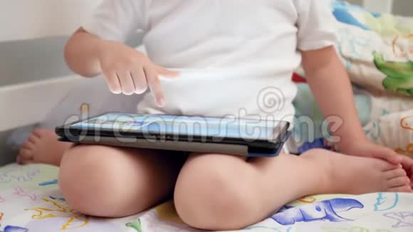 4k小男孩坐在床上用手指按数字平板触摸屏的特写视频视频的预览图