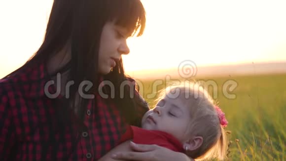 年轻漂亮的妈妈和婴儿一起在公园里散步小女儿睡在一位有爱心的母亲的怀里视频的预览图