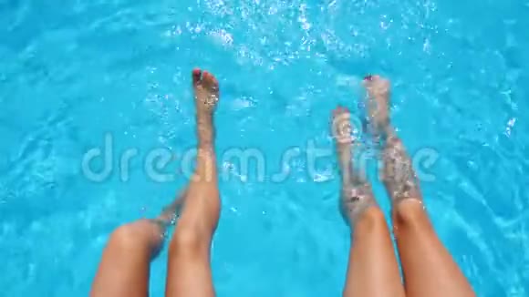 年轻女子坐在池边双脚悬在水里两个黝黑的小女孩在附近放松视频的预览图
