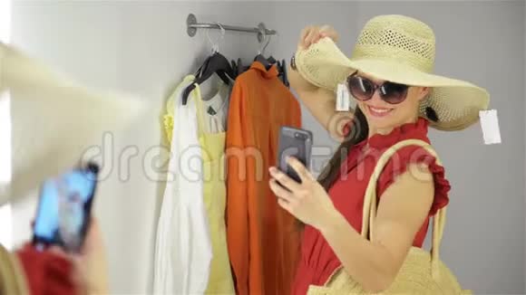 幸福的年轻女子站在服装店的化妆室里女孩在更衣室附近拍照视频的预览图