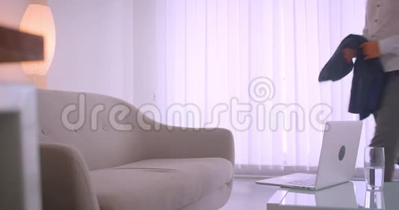 特写侧景用笔记本电脑在公寓里的沙发上悠闲地坐着白种人商人的画像视频的预览图