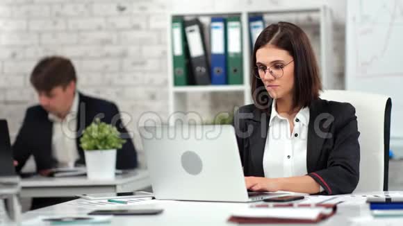 专注于时尚的年轻商务女性和男性在现代工作场所看笔记本电脑屏幕视频的预览图