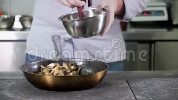 厨房餐厅的厨师把手放在盛有蘑菇和洋葱的热锅上的鹿肉上视频的预览图