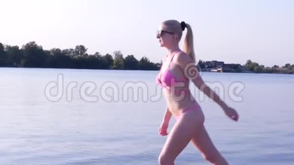 穿比基尼的性感女孩光着脚在湖岸上翻手视频的预览图