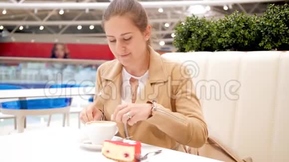 4K画面显示一位年轻的微笑女子坐在咖啡馆里打开纸袋装满糖倒在咖啡杯里喝着视频的预览图