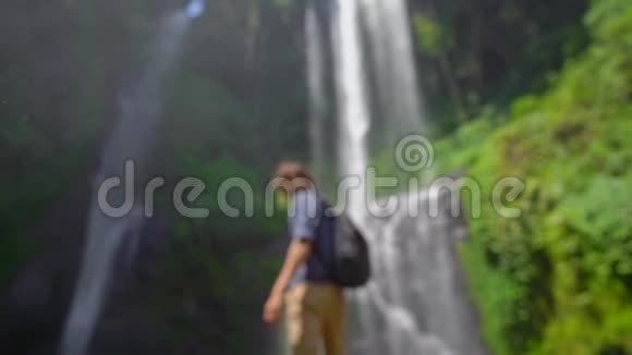 年轻人游览巴厘岛上最大的瀑布塞库普尔瀑布慢镜头旅费视频的预览图