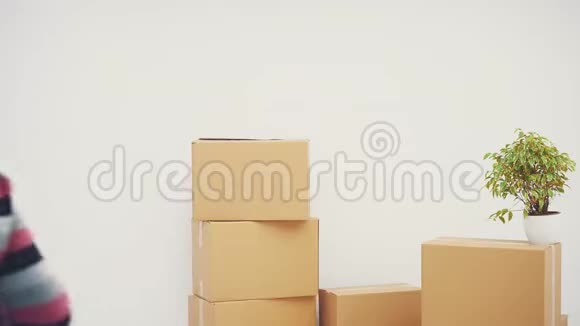 年轻人站在他的新公寓里靠在一堆纸箱上微笑着拿出新房子的钥匙视频的预览图