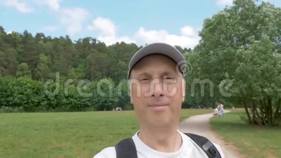 中年男子走在公园里正在拍摄特写镜头视频的预览图