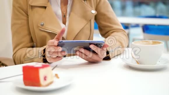4k特写视频年轻女性坐在咖啡屋的桌子后面在智能手机上输入信息视频的预览图