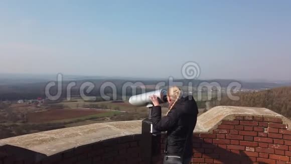 有魅力的女旅行者用望远镜观察古堡附近的山谷视频的预览图