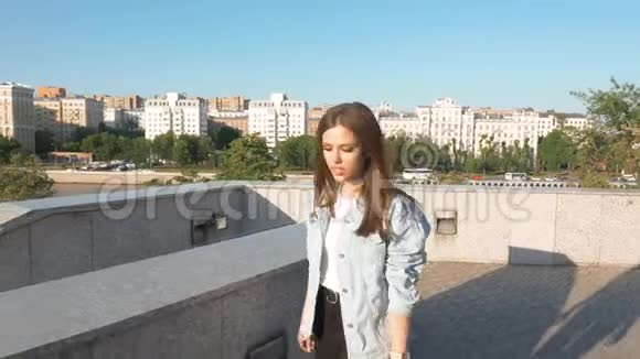 一位留着长发的美丽女孩在夕阳的背景下在城市里唱歌视频的预览图