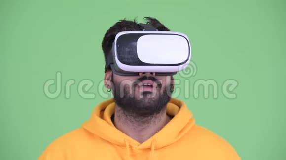 使用虚拟现实耳机的年轻体重超重留胡子的印度男人的脸视频的预览图