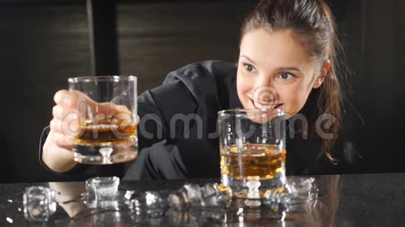 酒吧和鸡尾酒概念穿着黑色制服的女酒保在做鸡尾酒时对着镜头微笑夜间生活概念视频的预览图