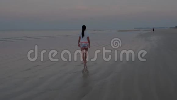 泰国普吉岛高拉克海滩日出时白色海滩上有棕榈树女人在海滩上散步视频的预览图