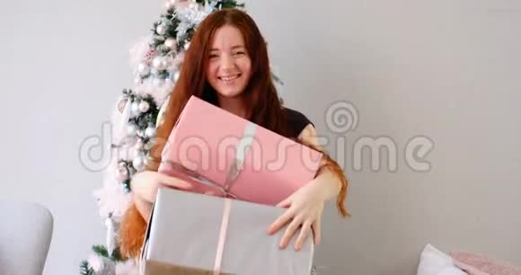 一位留着红色长发的女士在圣诞树旁的礼物中尽情享受视频的预览图