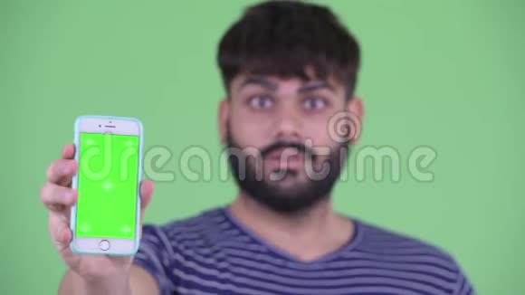 年轻体重超重留胡子带着手机竖起大拇指的印度男人的脸视频的预览图