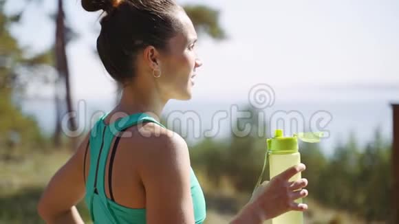 漂亮的女孩慢跑后从塑料瓶里喝水视频的预览图
