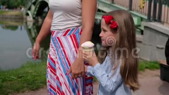 小女孩吃着冰淇淋牵着妈妈的手夏季户外活动视频的预览图