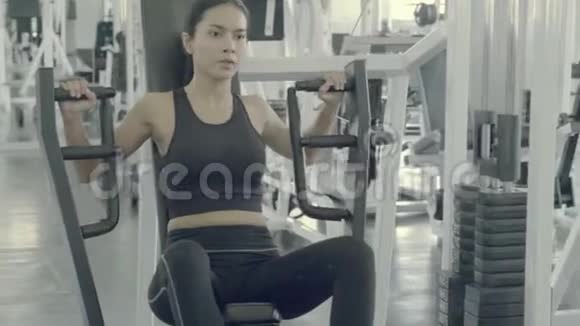 美丽的亚洲年轻女子在健身器上锻炼身体肌肉手臂视频的预览图