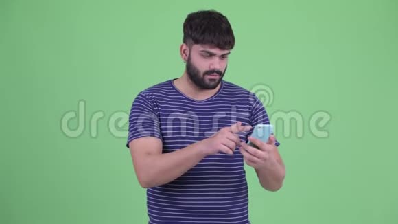 快乐年轻体重超重留着胡子的印度男人用电话得到好消息视频的预览图