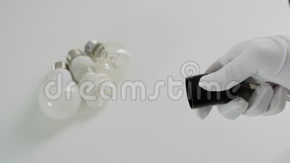 男性手扭转电器节省灯泡在白色桌子上快关门视频的预览图