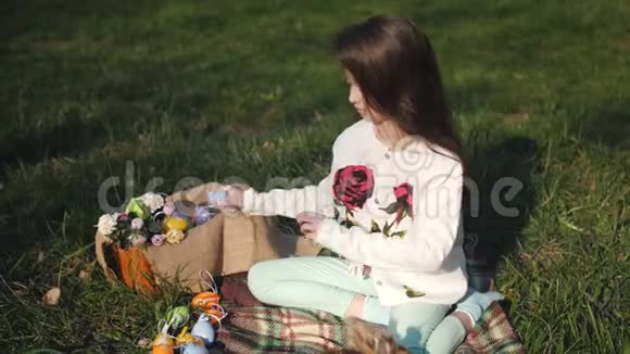 院子里的女孩坐在草地上的毯子上拍拍复活节兔子视频的预览图