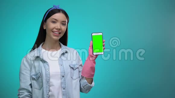 戴手套的女孩用绿色屏幕指着智能手机提供清洁服务视频的预览图