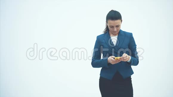 严肃的商业女性在白色背景握住手机看着特写视频的预览图