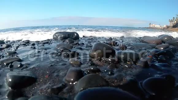 特写慢动作视频海浪在沙滩上翻滚的黑色卵石视频的预览图