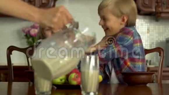 女用手在杯子里倒牛奶给前景的孩子们两个孩子在里面胡闹视频的预览图