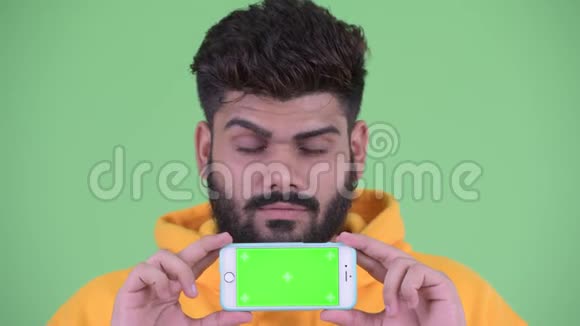 年轻体重超重留胡子的印度男人一边看手机一边思考视频的预览图