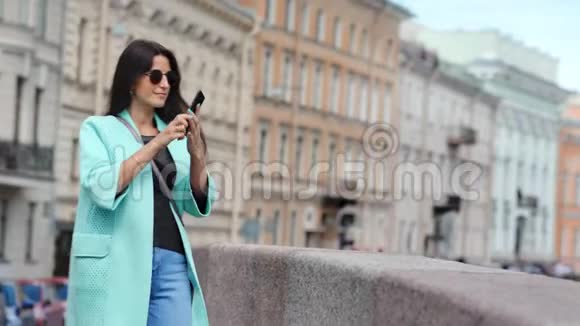 微笑时尚年轻旅行女性用智能手机拍照欣赏历史建筑视频的预览图