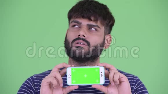 年轻体重超重留胡子的印度男人一边看手机一边思考视频的预览图