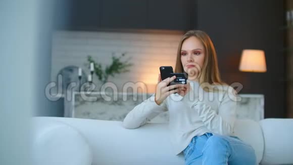 一个快乐微笑的女人手里拿着一部智能手机用手机银行在线购买视频的预览图