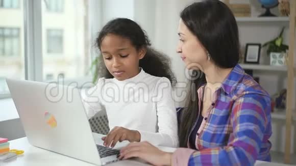 年轻的非洲女孩同意白种人的导师在网上学习使用新的现代技术笔记本电脑视频的预览图