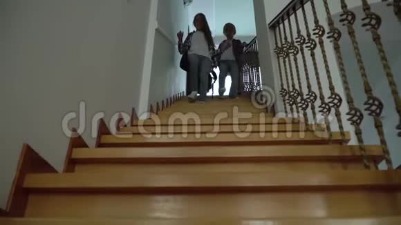 两个快乐的学童背着背包走下楼梯小兄弟刚放学回家友好快乐视频的预览图