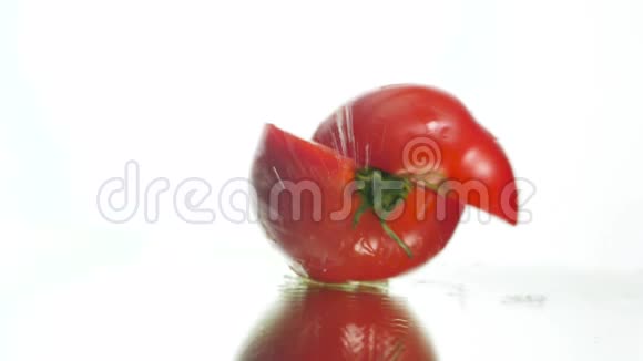 特写鲜红色番茄落在湿反光表面两片劈裂的慢动作视频概念视频的预览图