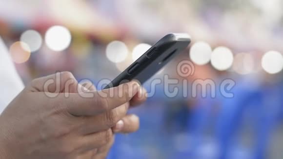 手中的妇女短信在手机智能手机上交流和聊天在社会网上在街头食品市场视频的预览图