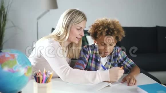 女人和小非洲男孩正在家里学习新的学校练习写作任务视频的预览图