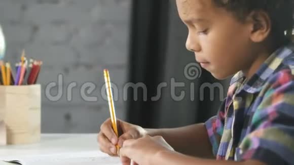 美国的非洲男孩坐在教室的桌子旁在教育笔记本上做作业视频的预览图